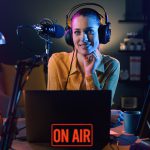 Young smiling radio host talking into a microphone and broadcasting at the radio station, entertainment and communication concept